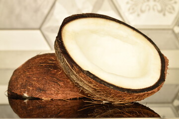Two half of a ripe coconut, close-up, on a background of tiles.