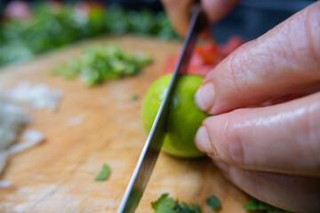Hands slicing a lime on a cutting board