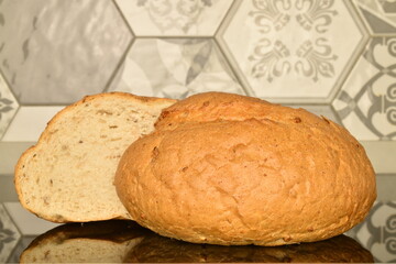 Two halves of fragrant white bread, close-up, on the background of tiles.