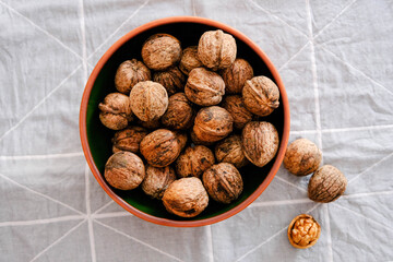 The image of walnuts in a ceramic bowl on a gray background
top view.