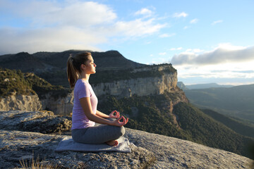 Fototapeta na wymiar Profile of a woman doing yoga in the top of a cliff