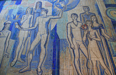 Obraz premium Osh, Kyrgyzstan - 09.09.2019: Tajikistan - Soviet mosaic closeup detail. Detail of old antique mosaic. Typical plot of street art of USSR period. Mass street culture of primitive Soviet poster. 