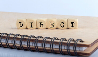 word DIRECT made with letters on wooden blocks on wooden notepad
