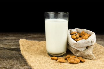 Milk with almond or roasted almond on sack with a wooden table on dark background. Healthy food. Snack. Food and drink concept.