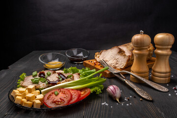 baked pork with herbs, tomatoes, cheese on a dark background