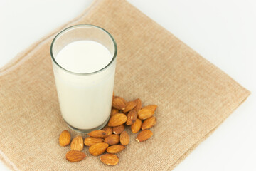Milk in the glass with almond or roasted almond on sack with white background. Healthy food. Snack. Food and drink concept.