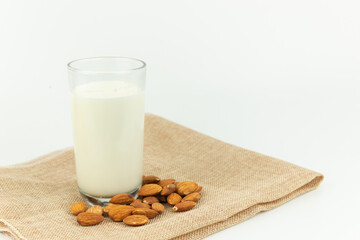 Milk in the glass with almond or roasted almond on sack with white background. Healthy food. Snack. Food and drink concept.