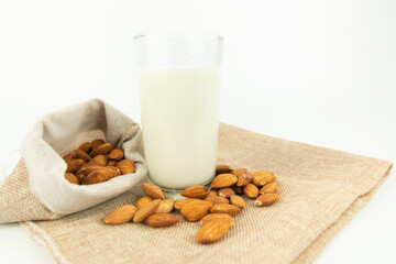 Milk in the glass with almond or roasted almond on sack with white background. Healthy food. Snack. Food and drink concept.
