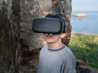 Teenager with virtual reality glasses in the countryside watching a ruin
