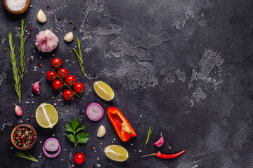 Herbs and condiments on black stone background.