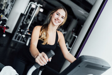 Fototapeta na wymiar Portrait of a smiling girl on a cardio machine, healthy look, healthy body