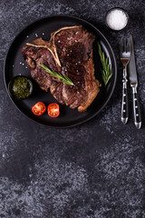Grilled beef steak with spices on a black plate