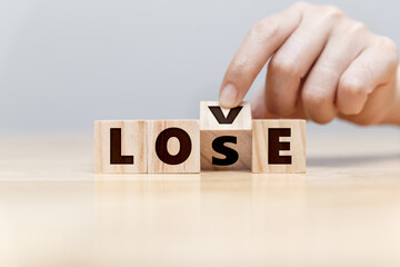 Hand of man try to fix wording of LOVE and LOSE on wooden block