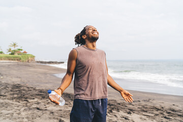 Happy black man enjoying summer day on beach after workout