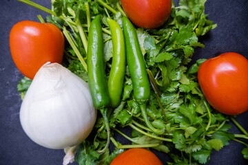 Chili peppers, onion, and a tomato above coriander