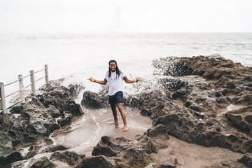 Optimistic black man resting on rocky beach