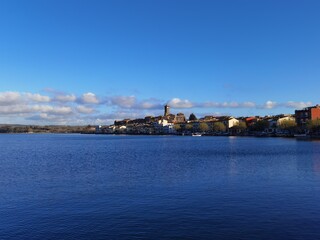 View of a small village on the coastline under a blue sky with scattered clouds.