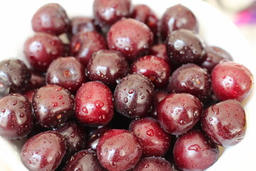 Freshly washed cherry berries lie on a white plate.