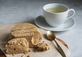 Halva sunflower - sweet dessert and green tea in a white cup on a light background. Selective focus.