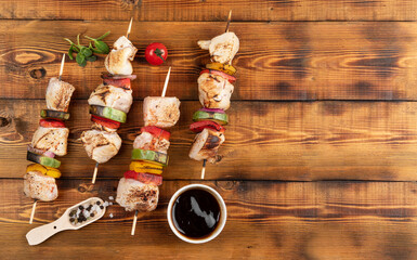 Chicken shish kebab on wooden skewers lies on the board. Sauce, spices. Place for the label.