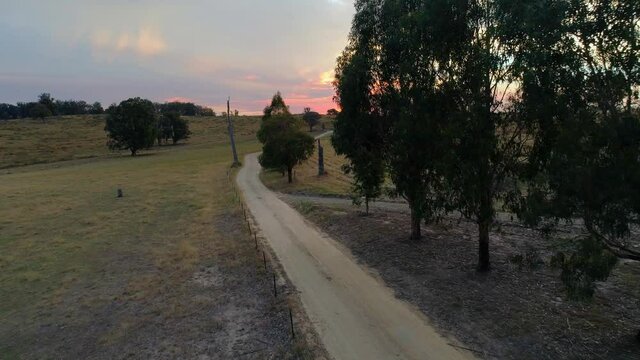 Forward flight over dirt road rising high to reveal beautiful sunset