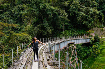 Happy woman with open arms on a big bridge an old railway track