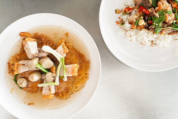 vermicelli fried noodles topping with Crispy pork in Gravy Sauce on white plate, Thai Asian style food. Copy space