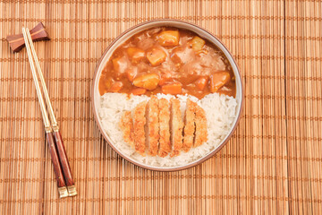 Top view Japanese curry rice topping with fried pork and vegetables in white and black plate with chopsticks. Curry rice Japanese food.
