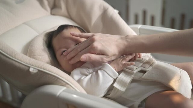asian woman mother gently touching baby infant head with care lull to sleep on baby buggy at home. baby sleeping on baby stroller. natural authentic.