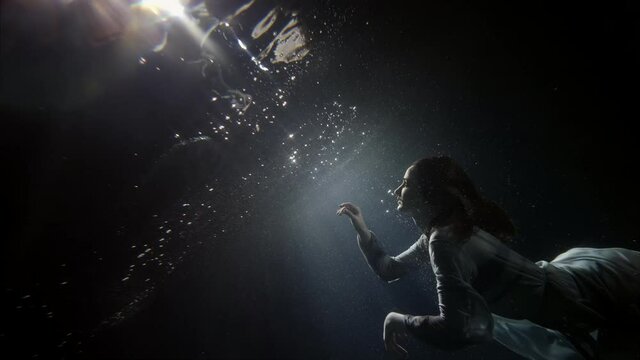 beautiful young woman is floating under water surface, magic subaquatic slow motion shot