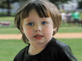 portrait of a little child with blue eyes and bang-cut hair.  Grandaughter at her sister's softball game in Windsor in Broome County in Upstate NY.