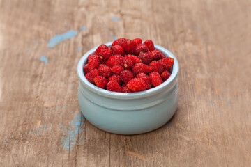 Red strawberries in blue ceramic bowl on wooden board, top view. Organic berries, healthy eating background