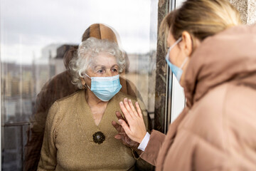 Woman visiting her grandmother in isolation during a coronavirus pandemic
