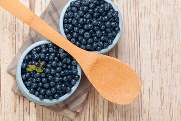 Blueberries in blue plate with spoon on white vintage wooden board background. Healthy eating