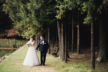 Beautiful romantic wedding couple of newlyweds hugging in park