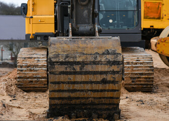 Fototapeta na wymiar Yellow excavator bucket on the sand