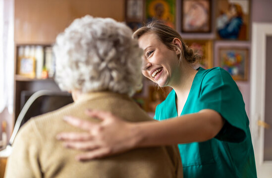 Friendly nurse supporting an elderly lady
