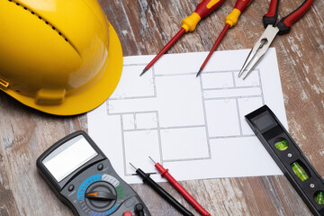 Composition of construction tools. Blueprint, multimeter, yellow helmet and screwdrivers on wooden board. Construction concept. 