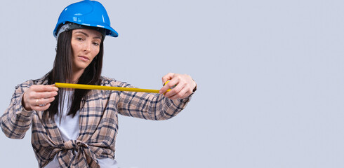 Banner,long format. Focused brunette woman in hard hat with tape measure on white background with blank space.