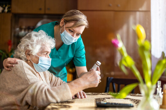 Home caregiver helping senior woman with medication
