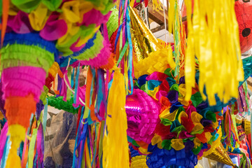Colorful pinatas with paper stripes hanging inside a market