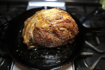 Prime rib roast baked on a cast iron skillet in a home kitchen.