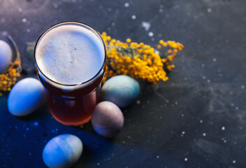 A glass of beer on the table with Easter eggs, a copy space card