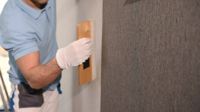 Vinyl Wallpaper Installation with Squeegee Tool. Caucasian Men Applying Material on a Wall.