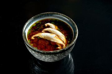 Japanese miso soup with onions, seaweed and eryngii mushrooms, served in a black bowl. Isolated on a black background. Diet food