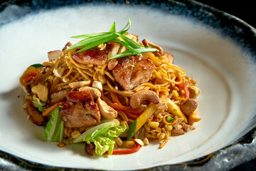 Sweet and sour noodles with pork, peanuts, vegetables and onions, served in a white bowl. Wok noodles. Isolated on a black background. Street thai food