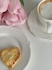 Morning breakfast with cup of coffee and biscuits in the background pink flower tulips
