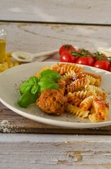 spirili pasta mit Tomatensoße und hackfleischbällchen auf weissem teller 