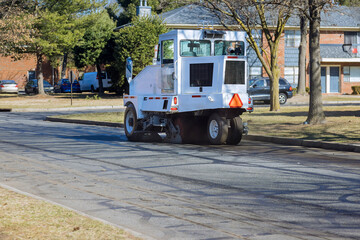 Cleaning sweeper machines washes the asphalt road with water spray of the town.