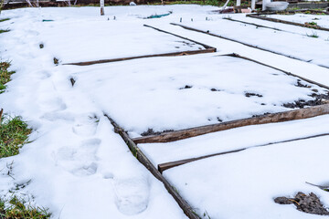 Home garden beds are covered with snow in spring, unexpected snow for gardeners